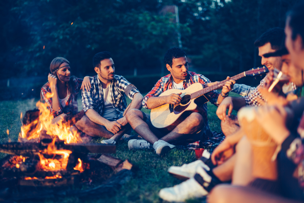 guitar player friends campfire