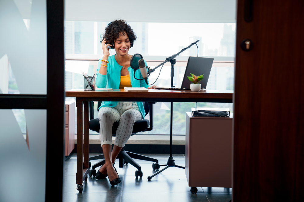 a woman records at desk using a condenser mic