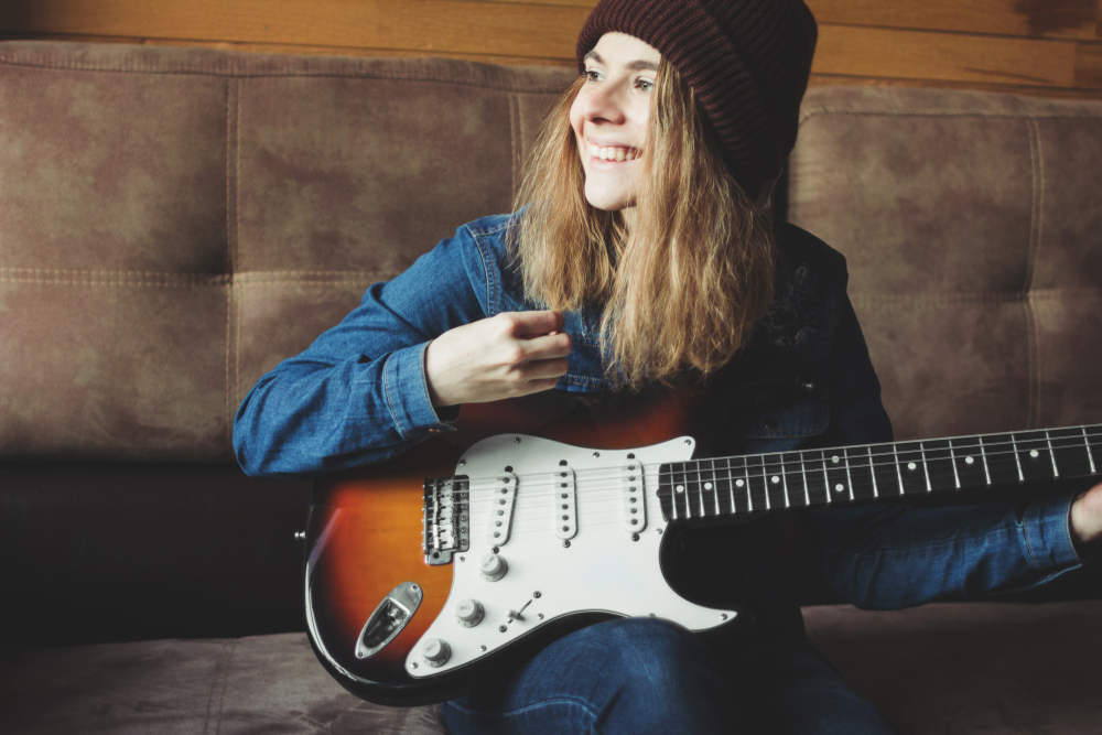 woman holds Fender electric guitar
